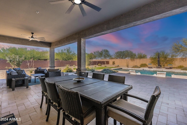 patio terrace at dusk with a fenced in pool and ceiling fan