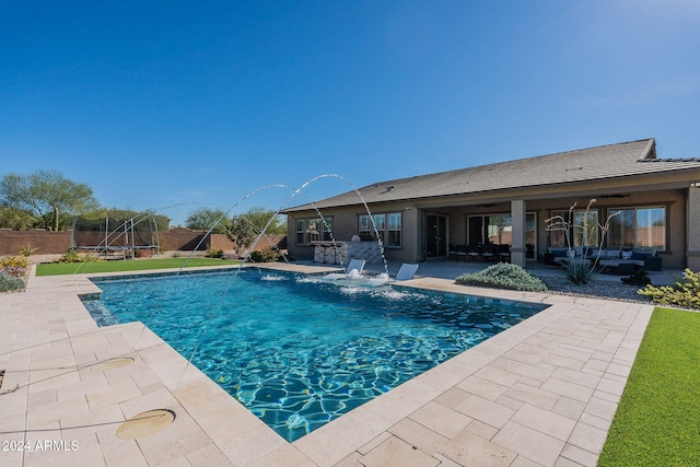 view of pool featuring pool water feature, a patio, an outdoor living space, and a trampoline