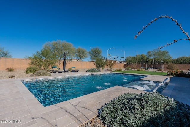 view of swimming pool featuring a patio, a trampoline, and pool water feature