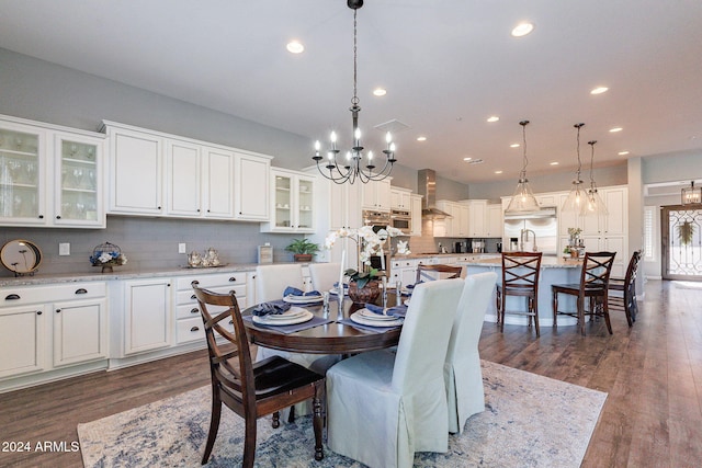 dining room with sink, dark hardwood / wood-style flooring, and an inviting chandelier