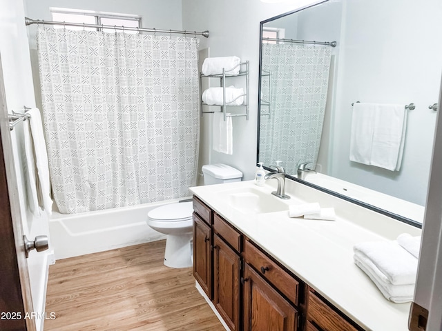 full bathroom with hardwood / wood-style flooring, vanity, shower / tub combo with curtain, and toilet