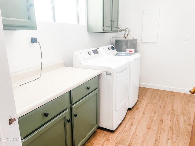 laundry area with light hardwood / wood-style floors, cabinets, washing machine and dryer, and water heater