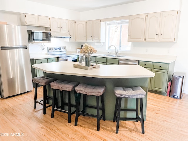 kitchen with sink, a kitchen island, a breakfast bar, and appliances with stainless steel finishes