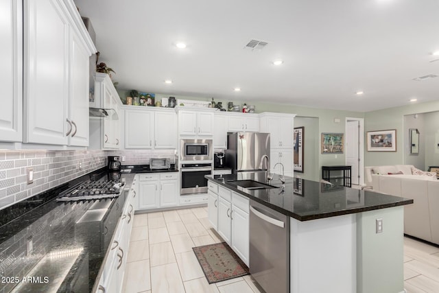 kitchen featuring tasteful backsplash, visible vents, appliances with stainless steel finishes, white cabinets, and a sink