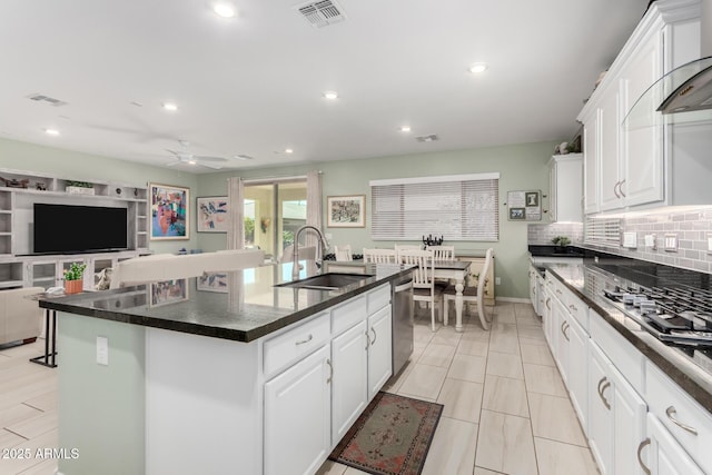 kitchen with visible vents, dishwasher, decorative backsplash, white cabinetry, and a sink