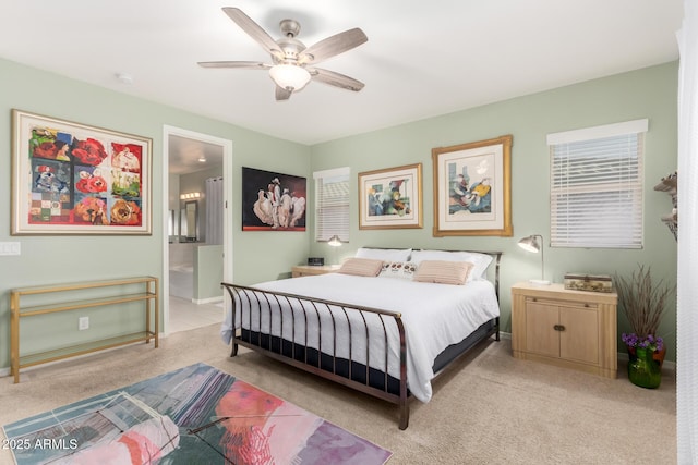 bedroom with light colored carpet, baseboards, ensuite bathroom, and a ceiling fan