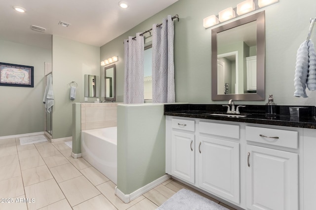 bathroom featuring vanity, a shower with shower door, baseboards, visible vents, and a garden tub