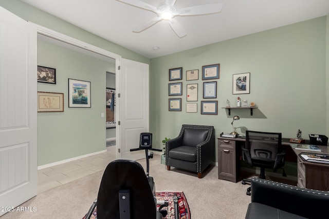 office area with a ceiling fan, light colored carpet, and baseboards