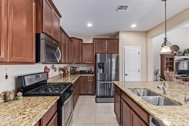 kitchen with hanging light fixtures, sink, light stone countertops, light tile patterned flooring, and appliances with stainless steel finishes