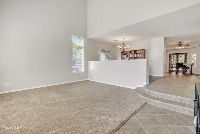 carpeted spare room featuring ceiling fan with notable chandelier