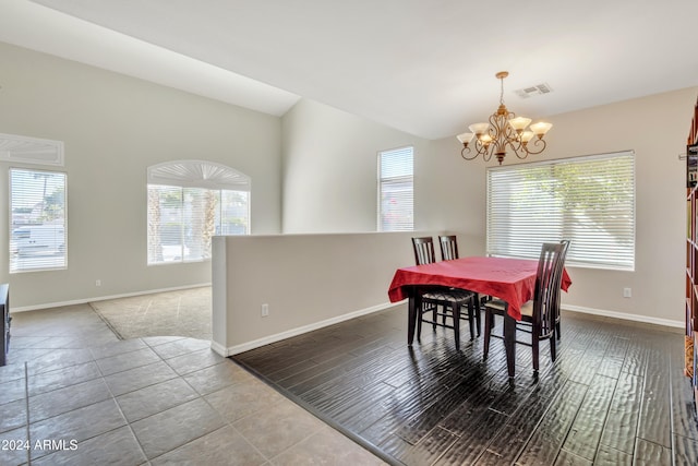 dining room with light wood-type flooring, vaulted ceiling, a wealth of natural light, and a notable chandelier