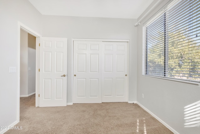unfurnished bedroom featuring light carpet and a closet