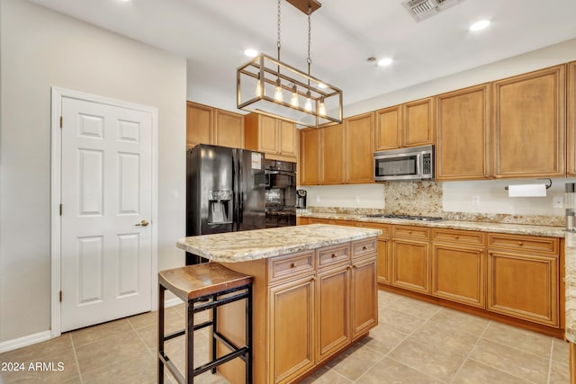 kitchen featuring light tile patterned flooring, hanging light fixtures, a kitchen island, a kitchen bar, and stainless steel appliances