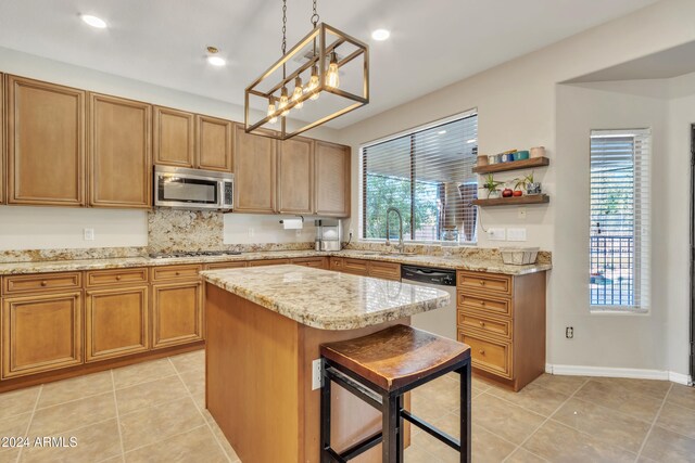 kitchen featuring stainless steel appliances, sink, decorative light fixtures, a kitchen island, and a breakfast bar area