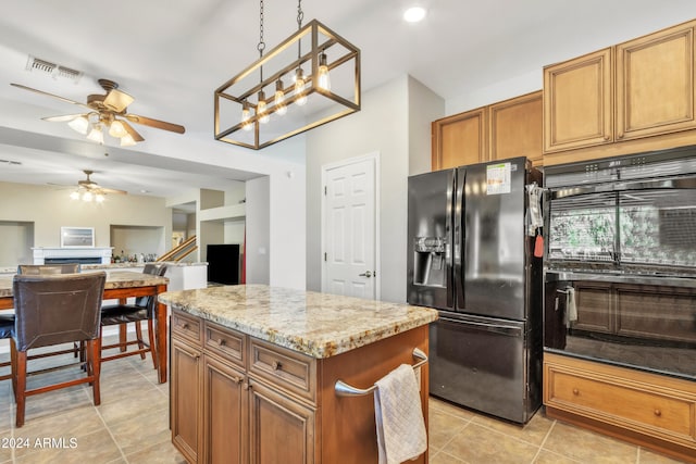 kitchen featuring light stone countertops, light tile patterned floors, decorative light fixtures, black fridge with ice dispenser, and a kitchen island