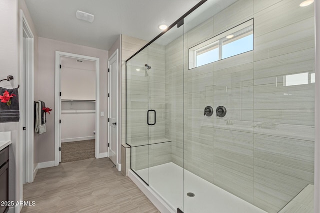 bathroom featuring a shower with door and vanity