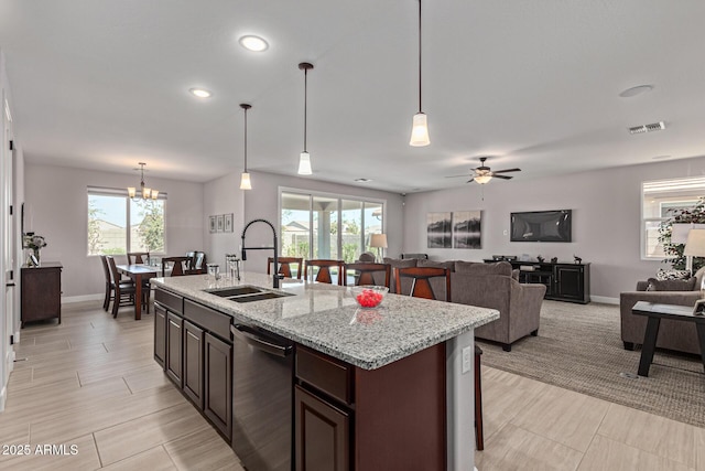 kitchen featuring dishwasher, sink, hanging light fixtures, a center island with sink, and ceiling fan with notable chandelier