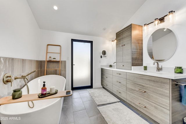 bathroom with tile patterned floors, a sink, recessed lighting, double vanity, and a soaking tub