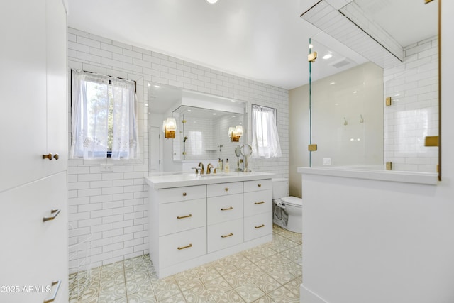 bathroom featuring tile patterned floors, toilet, tile walls, and a walk in shower