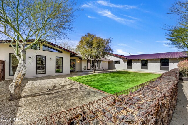 rear view of house with stucco siding, a patio, and a yard