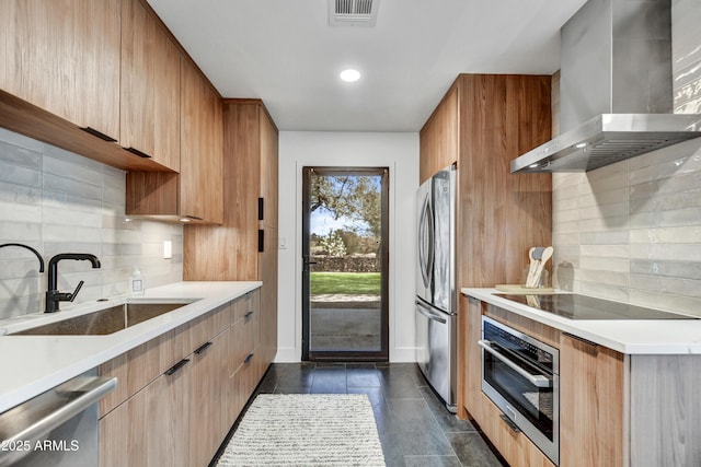 kitchen featuring visible vents, a sink, stainless steel appliances, wall chimney exhaust hood, and light countertops