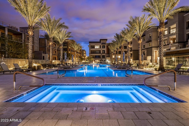 pool at dusk featuring a community hot tub and a patio