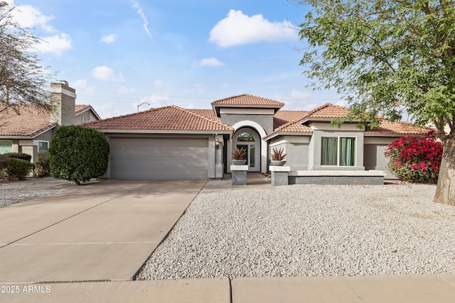 mediterranean / spanish home featuring driveway, an attached garage, a tile roof, and stucco siding