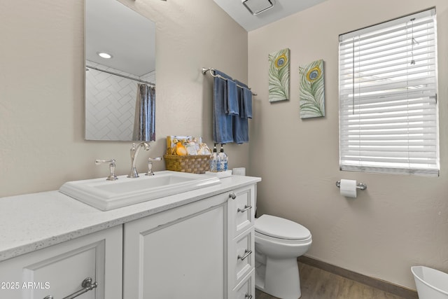 bathroom with baseboards, a shower with shower curtain, toilet, wood finished floors, and vanity