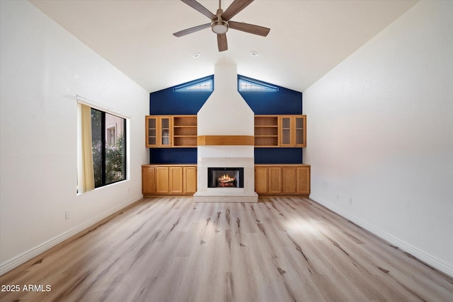 7565 N Via De La Siesta, Scottsdale, AZ 85258 - unfurnished living room with ceiling fan, light wood finished floors, a glass covered fireplace, high vaulted ceiling, and baseboards