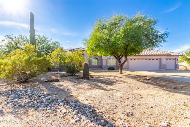 21 E Irvine Rd, Phoenix, AZ 85086 - view of property hidden behind natural elements featuring a garage, concrete driveway, a tile roof, and stucco siding