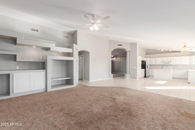 21 E Irvine Rd, Phoenix, AZ 85086 - unfurnished living room featuring a ceiling fan, arched walkways, light tile patterned floors, vaulted ceiling, and light colored carpet