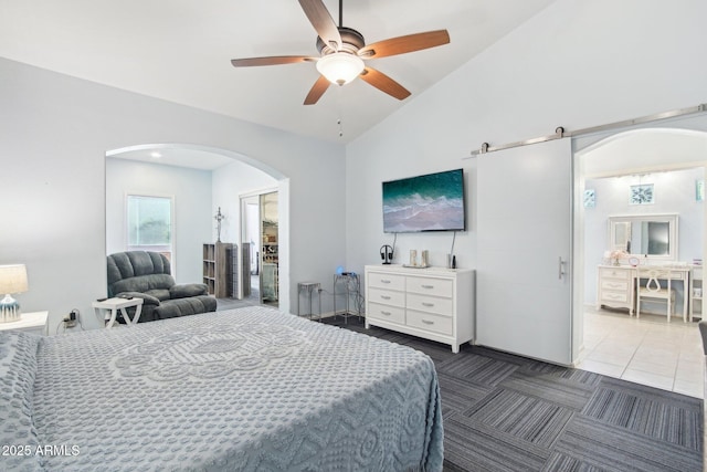 bedroom with vaulted ceiling, a barn door, and ceiling fan