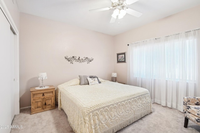 bedroom with ceiling fan, light carpet, and a closet