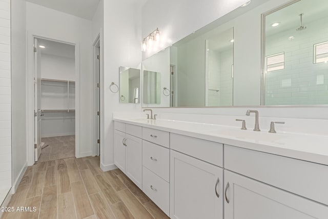 21952 E Saddle Ct E, Queen Creek, AZ 85142 - bathroom featuring double vanity, wood finished floors, tiled shower, a spacious closet, and baseboards