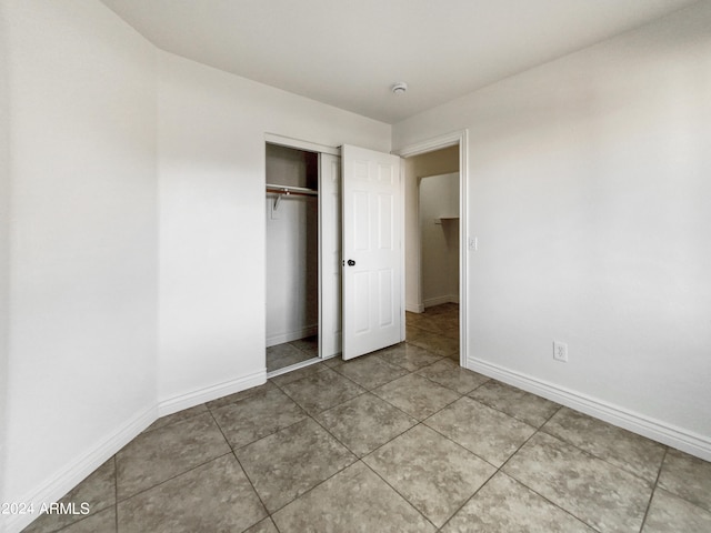 unfurnished bedroom with tile patterned flooring and a closet