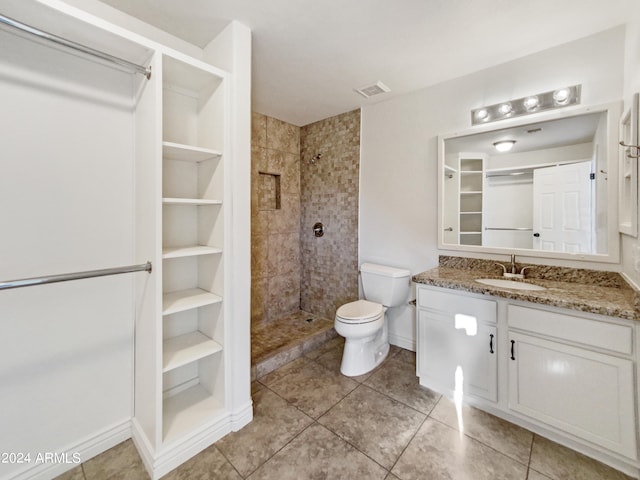 bathroom with tiled shower, vanity, toilet, and tile patterned floors