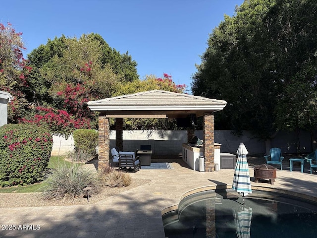 view of patio with an outdoor living space with a fire pit, a gazebo, fence, and a grill