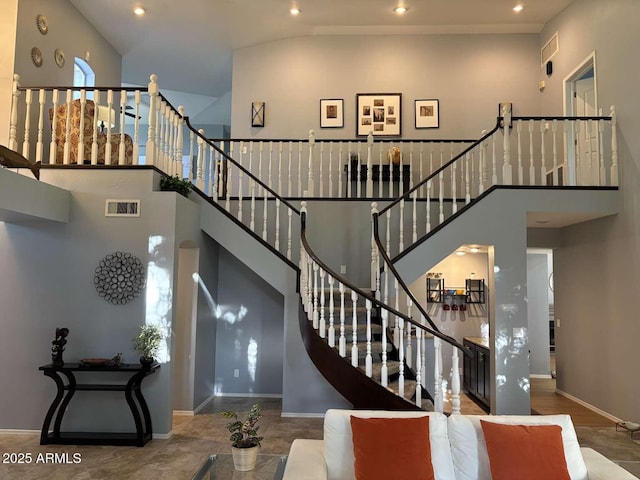 stairway with a high ceiling, baseboards, visible vents, and recessed lighting