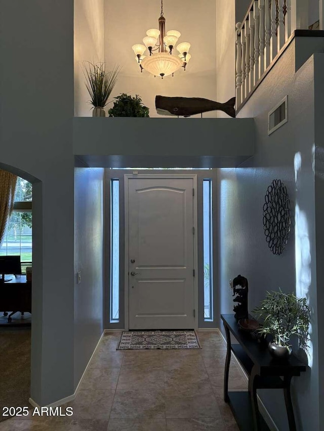 foyer with arched walkways, a high ceiling, a notable chandelier, and visible vents