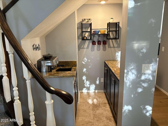 kitchen featuring dark stone countertops, baseboards, and dark cabinets