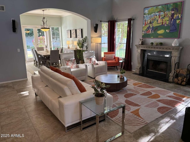 living room featuring ornamental molding, arched walkways, a high end fireplace, and a healthy amount of sunlight