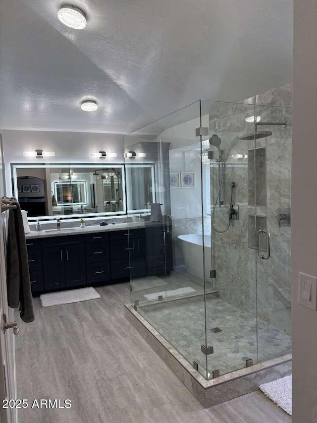 full bathroom featuring a stall shower, wood finished floors, and vanity