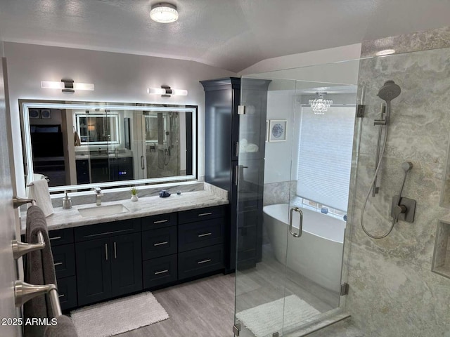 full bath with a freestanding bath, a shower stall, vanity, wood finished floors, and vaulted ceiling
