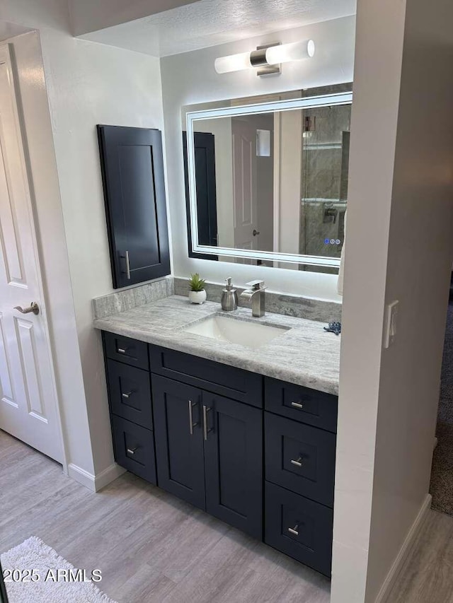 bathroom featuring vanity, baseboards, and wood finished floors