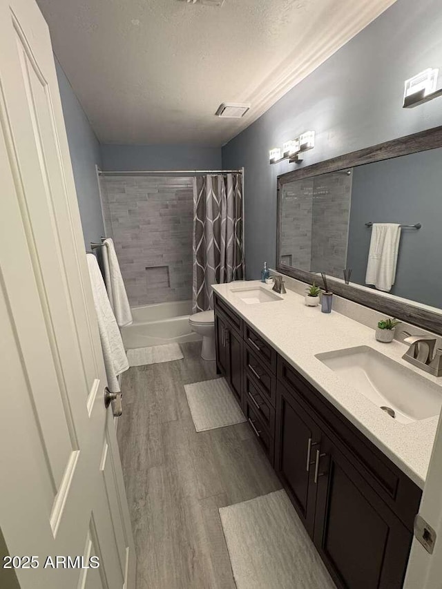 bathroom featuring a sink, shower / tub combo, toilet, and wood finished floors