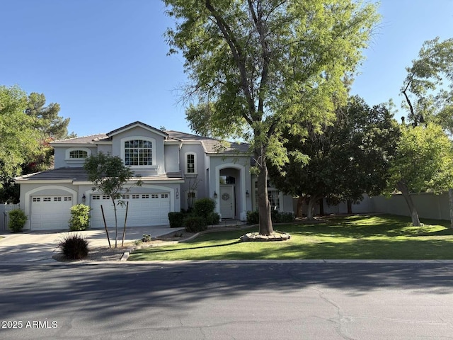 view of front facade with stucco siding, fence, a front lawn, a garage, and driveway