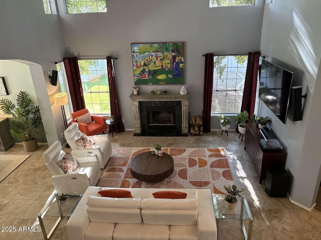 living room with a fireplace, a high ceiling, and baseboards