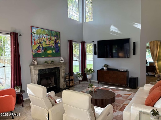 living room with a wealth of natural light, a high end fireplace, and a towering ceiling