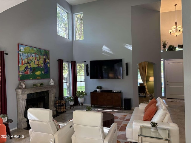 living room featuring a chandelier, baseboards, a high ceiling, and a fireplace