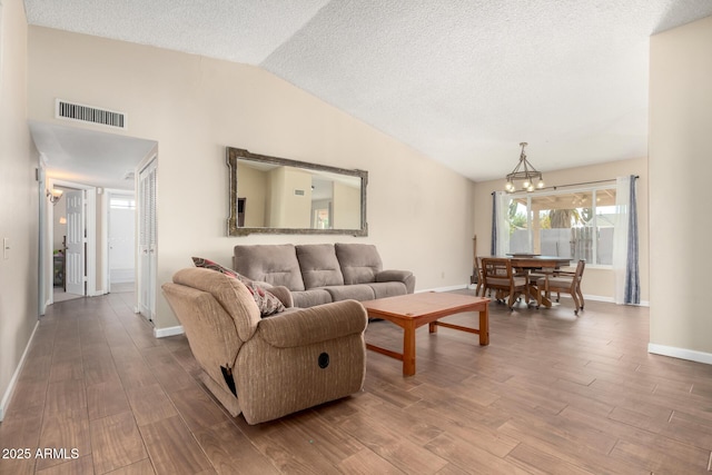 living room with a notable chandelier, wood-type flooring, lofted ceiling, and a textured ceiling